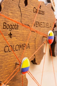 Colombia and Venezuela flags on the pushpin and red threads on the wooden map. Travel or logistic routes. Influence in geopolitics and world economy.