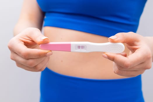 Close up woman holding a positive test near the belly.