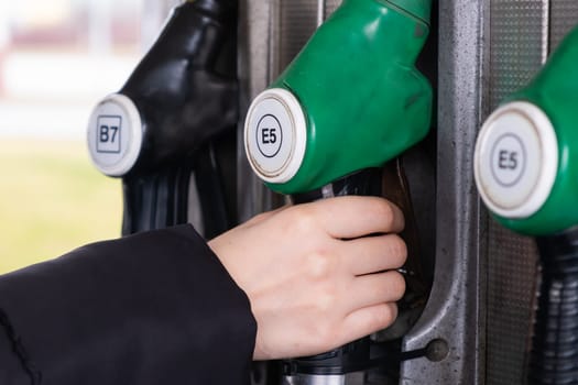 Petrol pump in a petrol station. Close up woman hand take oil dispenser with gasoline and diesel.