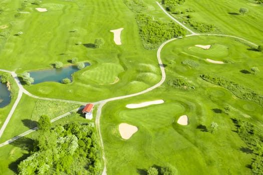 Golf course with sand bunker, green grass and pond, aerial view.