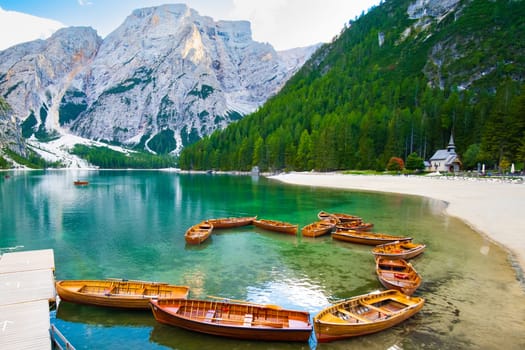 The magnificent Lake Braies with the chain of wooden boats in Dolomites Alps, Italy.