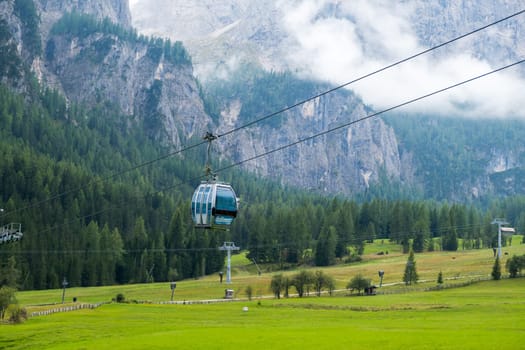 Cable car cabins against amazing Dolomites Alp covered with clouds.