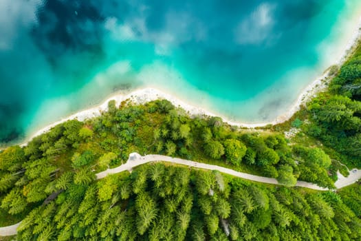 Aerial view of a lake with turquoise water and clouds reflection and pine trees on the shore.