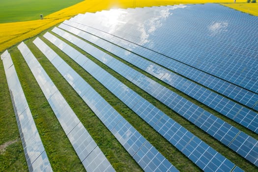 Solar power plant on the green field and yellow far away. Production of clean, cheap and green energy, aerial view