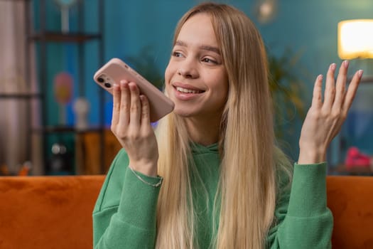 Happy excited woman making online phone call conversation with friends. Portrait of Caucasian girl enjoying mobile loudspeaker talking chatting communication at home apartment living room on couch
