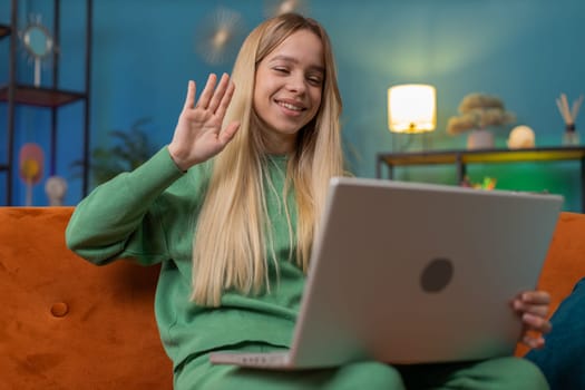 Caucasian woman sitting on couch looking at camera, making video webcam conference call with friends or family, enjoying pleasant conversation. Young girl laughing waving hello at home room apartment