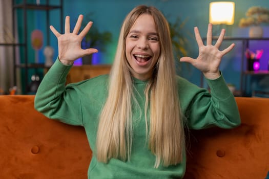 Happy Caucasian woman shouting, celebrating success, winning, goal achievement good news, lottery luck, victory, watching TV championship at modern home apartment. Girl in living room sitting on couch