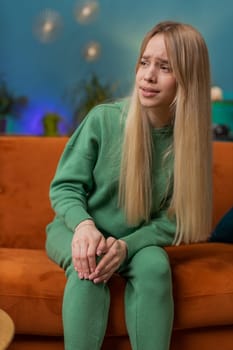Young woman suffer from painful severe knee joint ache, leg muscles, could not walk. Portrait of Caucasian girl massaging her knees illness cramps rheumatism at home room on sofa. Health care problem