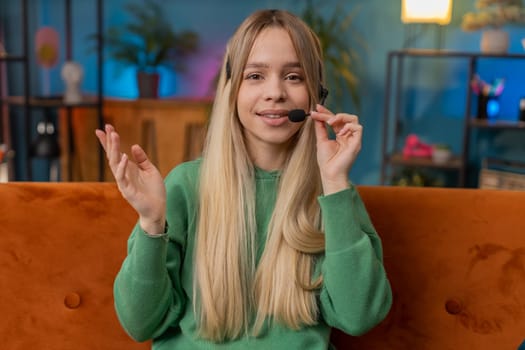 POV of Caucasian woman wearing headset, freelance worker, call center or support service operator helpline, having talk with client or colleague communication support waving hello. Girl at home room
