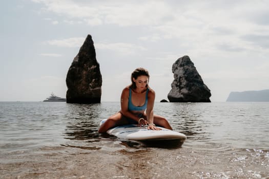 Close up shot of beautiful young caucasian woman with black hair and freckles looking at camera and smiling. Cute woman portrait in a pink bikini posing on a volcanic rock high above the sea