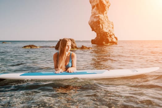 Close up shot of happy young caucasian woman looking at camera and smiling. Cute woman portrait in bikini posing on a volcanic rock high above the sea