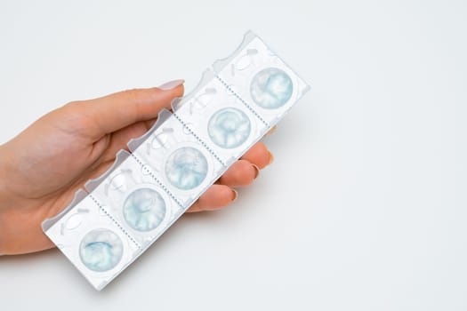 Blister with disposal contact lenses in womans hands on the white background.