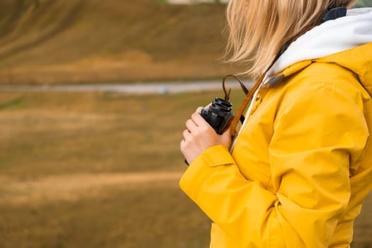 Woman in a yellow jacket with binoculars in the valley enjoying the view. Travel concept.