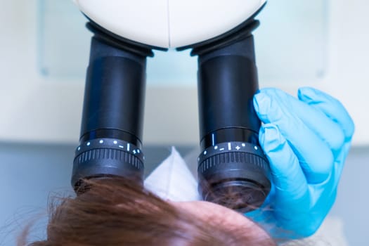 Professional female scientist doing experiment with electronic microscope in scientific genetic research laboratory