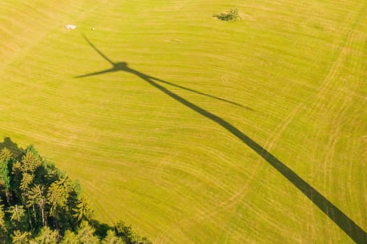 A shadow of a windmill on the yellow field. Renewable energy production concept.