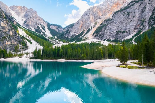 Sunny day on Lake Braies with turquoise water and high Dolomites mountains.