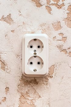 White double power socket on plaster wall in modern room interior.