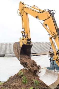 Excavation industrial work. A bulldozer pours out a bucket of land on a construction site close-up.