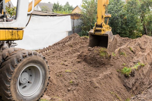 An excavator bucket digs the ground in an industrial area. Excavation construction work.