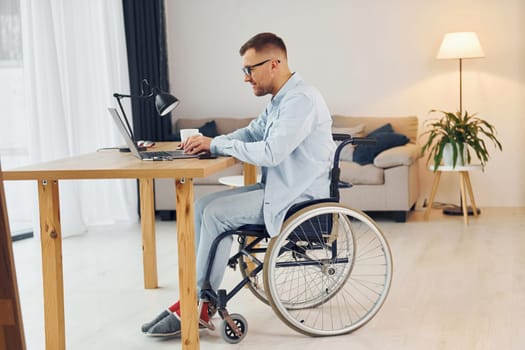 Smart freelance worker. Disabled man in wheelchair is at home.
