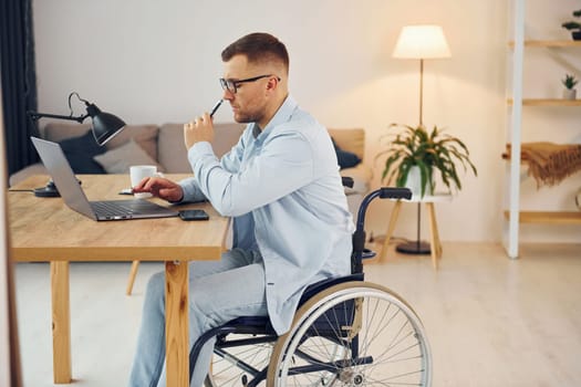 Smart freelance worker. Disabled man in wheelchair is at home.