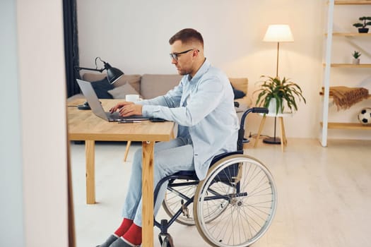 Smart freelance worker. Disabled man in wheelchair is at home.