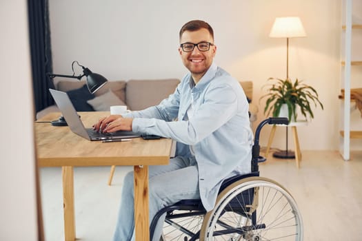 Smart freelance worker. Disabled man in wheelchair is at home.