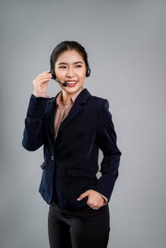 Attractive asian female call center operator with happy smile face advertises job opportunity on empty space, wearing a formal suit and headset on customizable isolated background. Enthusiastic