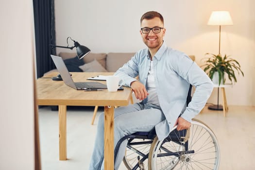 Cheerful disabled man in wheelchair is at home.