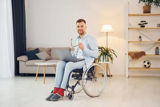 Cheerful disabled man in wheelchair is at home.