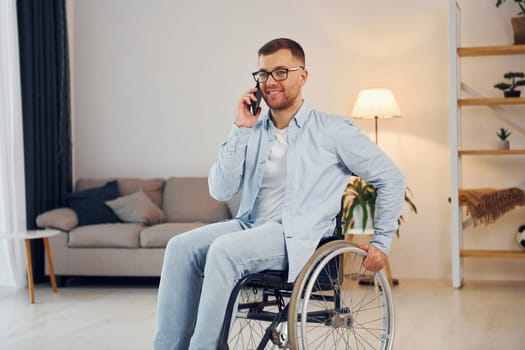 Talking by phone. Disabled man in wheelchair is at home.