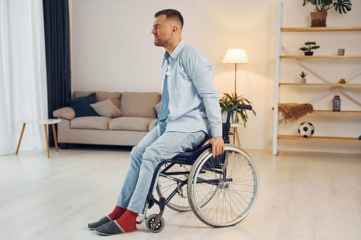 Trying to move. Disabled man in wheelchair is at home.
