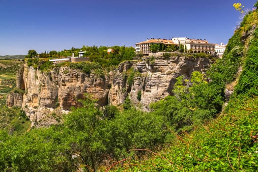 The rock cliffs on which the city of Ronda in Andalusia is built in sunshine and blue sky, Spain