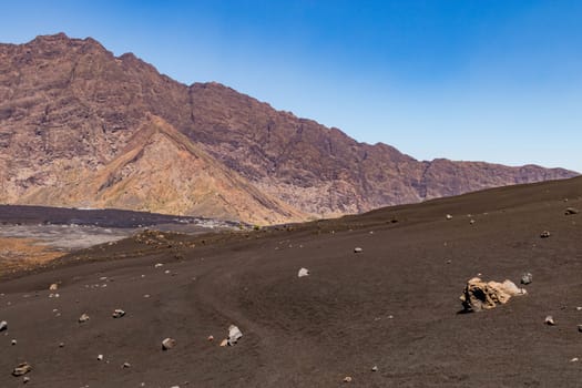 A footpath through dark lava rock on the mountainside of Pico do Fogo volcano on Fogo island, Cape Verde