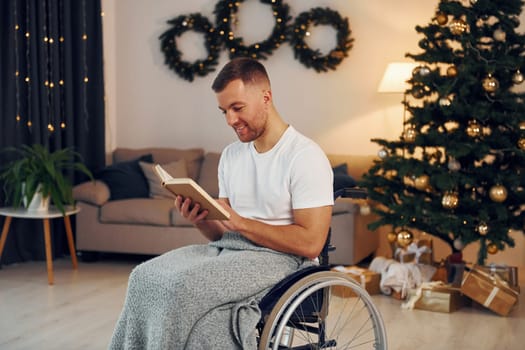 Reading the book. New year is coming. Disabled man in wheelchair is at home.