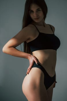 In dark room. Beautiful woman in underwear is posing indoors.