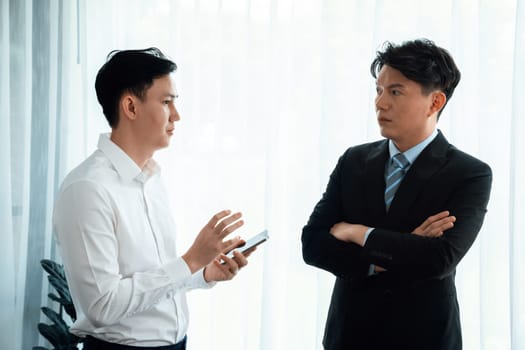 Manager advising guiding younger colleague with tablet in workplace. Couple businesspeople in formal wear working together on financial strategy as concept of teamwork and harmony in office.