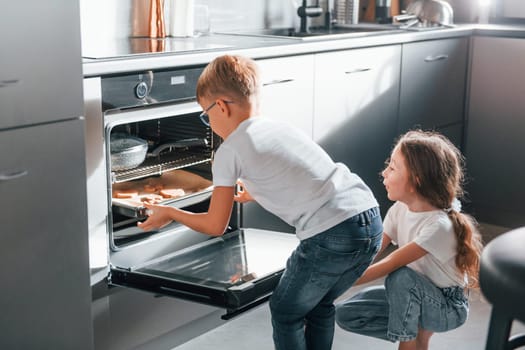 Baking food. Little boy and girl preparing Christmas cookies on the kitchen.