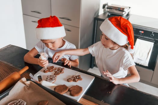 New year anticipation. Little boy and girl preparing Christmas cookies on the kitchen.