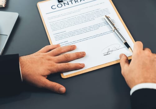 Closeup hand signing contract document with pen, sealing business deal with signature. Businesspeople finalizing business agreement by writing down signature on contract paper. Fervent