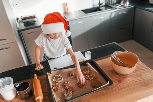 Little girl preparing Christmas cookies on the kitchen.