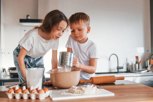 New year anticipation. Little boy and girl preparing Christmas cookies on the kitchen.