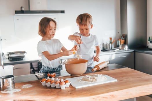 Working with dough. Little boy and girl preparing Christmas cookies on the kitchen.