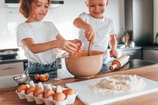 Working with dough. Little boy and girl preparing Christmas cookies on the kitchen.