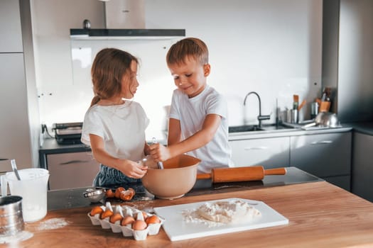 Preparing food together. Little boy and girl on the kitchen.
