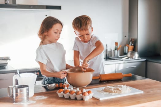 Preparing food together. Little boy and girl on the kitchen.