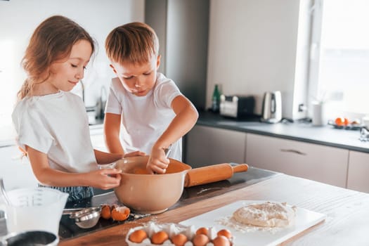 Preparing food together. Little boy and girl on the kitchen.