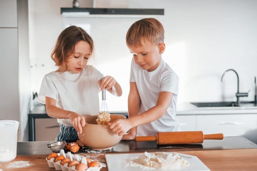 Preparing food together. Little boy and girl on the kitchen.