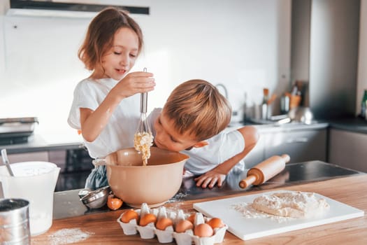 Weekend activities. Little boy and girl preparing Christmas cookies on the kitchen.