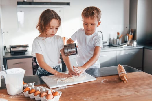 Weekend activities. Little boy and girl preparing Christmas cookies on the kitchen.